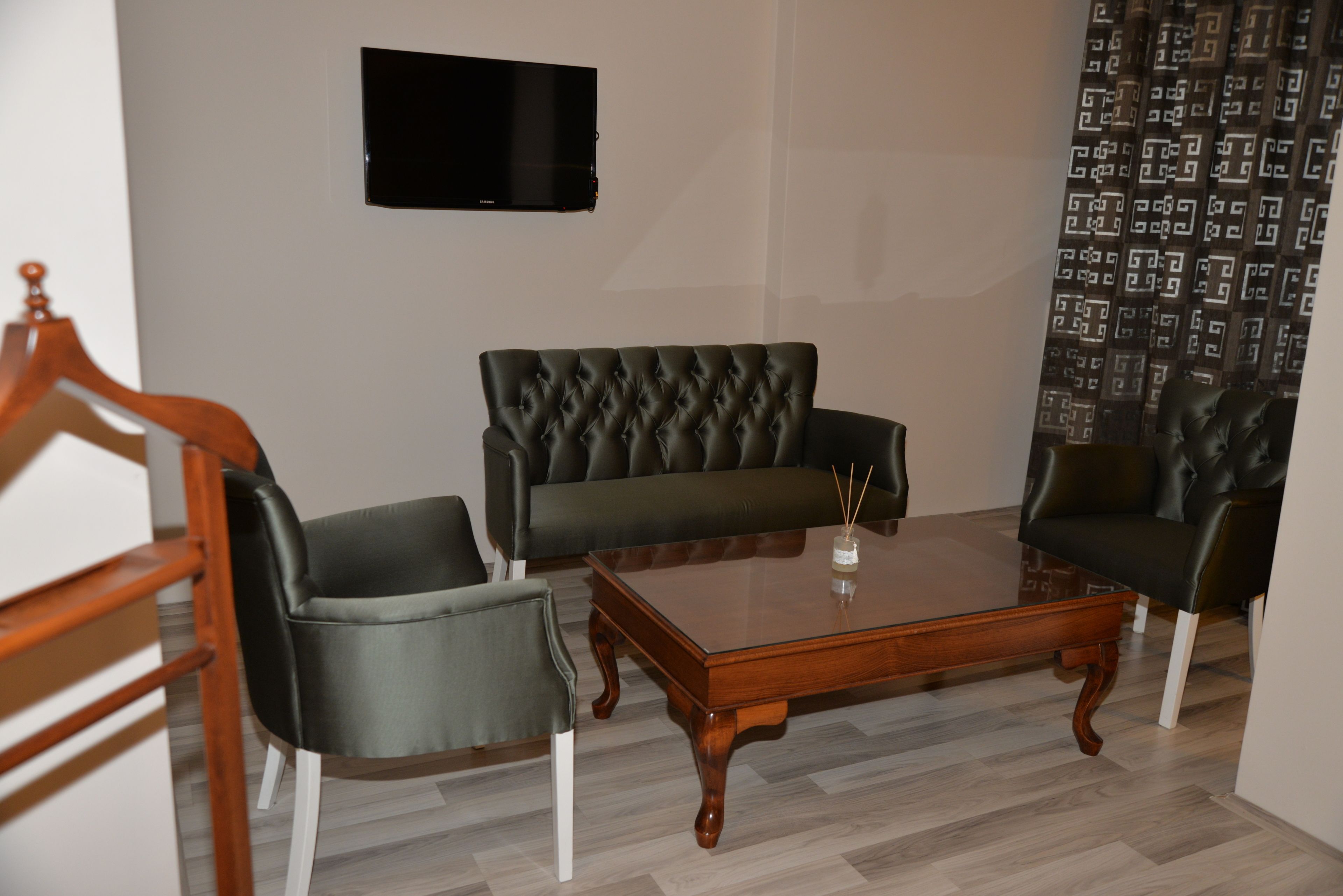 Un salon avec une table basse en bois, deux canapés en cuir noir et un téléviseur fixé au mur.