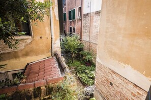 A narrow alleyway with a brick staircase leading down, surrounded by greenery and brick buildings. - MYSWEETPLACE - Santa Maria Formosa Apartment (Venice)