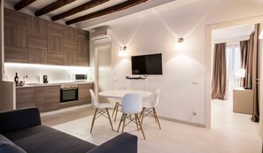 Cozy living space with a central dining area, kitchen, and flat-screen TV.
