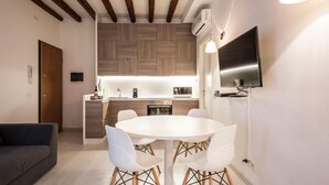 A modern kitchen with a central island, white dining table with chairs, and a flat-screen TV mounted on the wall. - MYSWEETPLACE - Santa Maria Formosa Apartment (Venice)
