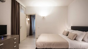 A hotel room with a bed, a TV, a desk, and a wardrobe. - MYSWEETPLACE - Santa Maria Formosa Apartment (Venice)
