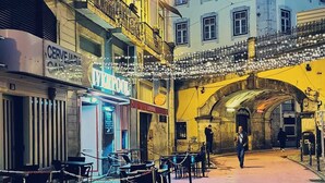 Una calle con mesas al aire libre, un café y un edificio con balcones.