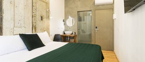 Une chambre d’hôtel comprenant un lit, une table de chevet, un miroir, un lavabo et un téléviseur.