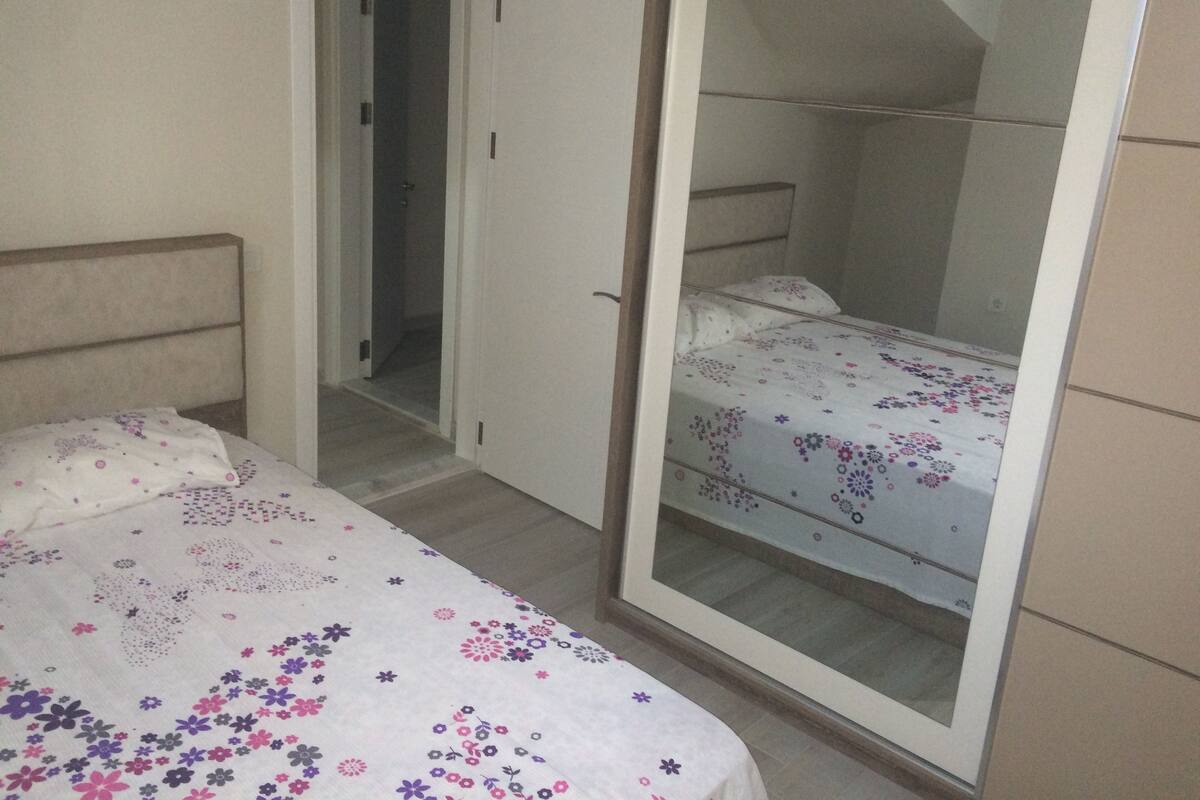 A bedroom with a bed, a wardrobe, and a door leading to another room.