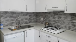 A kitchen with white cabinets, a stainless steel sink, a gas stove, and a dishwasher.