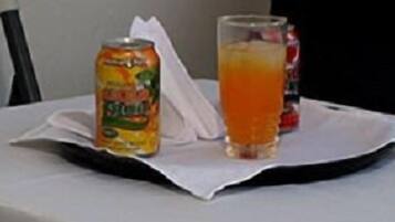Una lata de Sprite y un vaso de jugo de naranja sobre una mesa con mantel blanco.