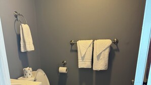A bathroom with a toilet, sink, and two towels hanging on a metal rack. - 12 Ashworth Ave (Hampton)