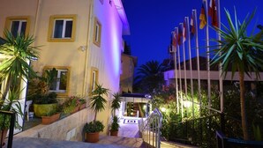 A hotel entrance with a staircase, potted plants, and multiple flags. - Muz Hotel - All Inclusive (Alanya)