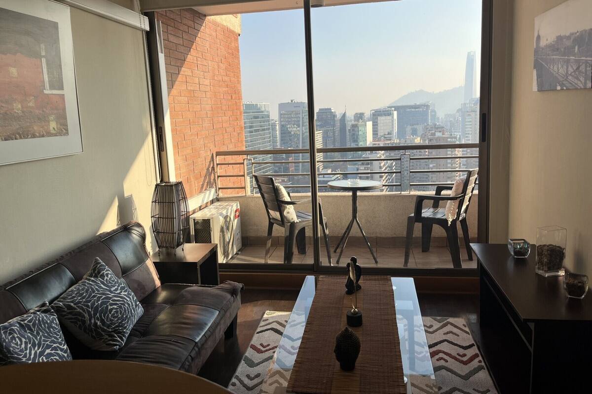 Un balcón con vistas a la ciudad, un sofá, una mesa y sillas.