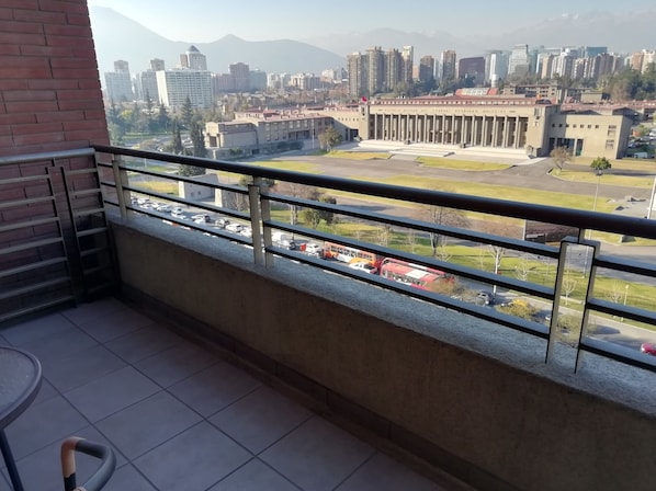A balcony with a view of a cityscape, including a large building with columns and a parking lot. - Cordova Savini (Santiago)