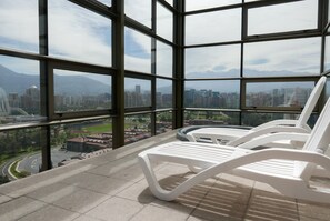 A high-rise building with a panoramic view of a cityscape and mountains. - Cordova Savini (Santiago)