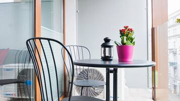 A balcony with a table, chairs, a potted plant, and a lantern.