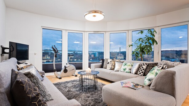 A modern living room with a large window, a sofa, a coffee table, and a TV.
