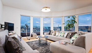 A modern living room with a large window, a sofa, a coffee table, and a TV. - Apartamenty Homely Place Centrum (Poznan)
