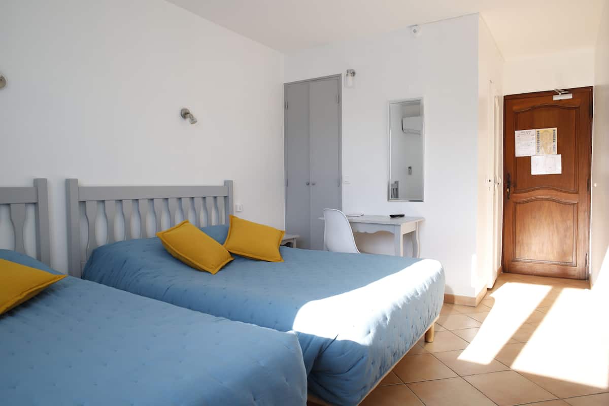 A bedroom with two beds, a desk, and a wooden door.