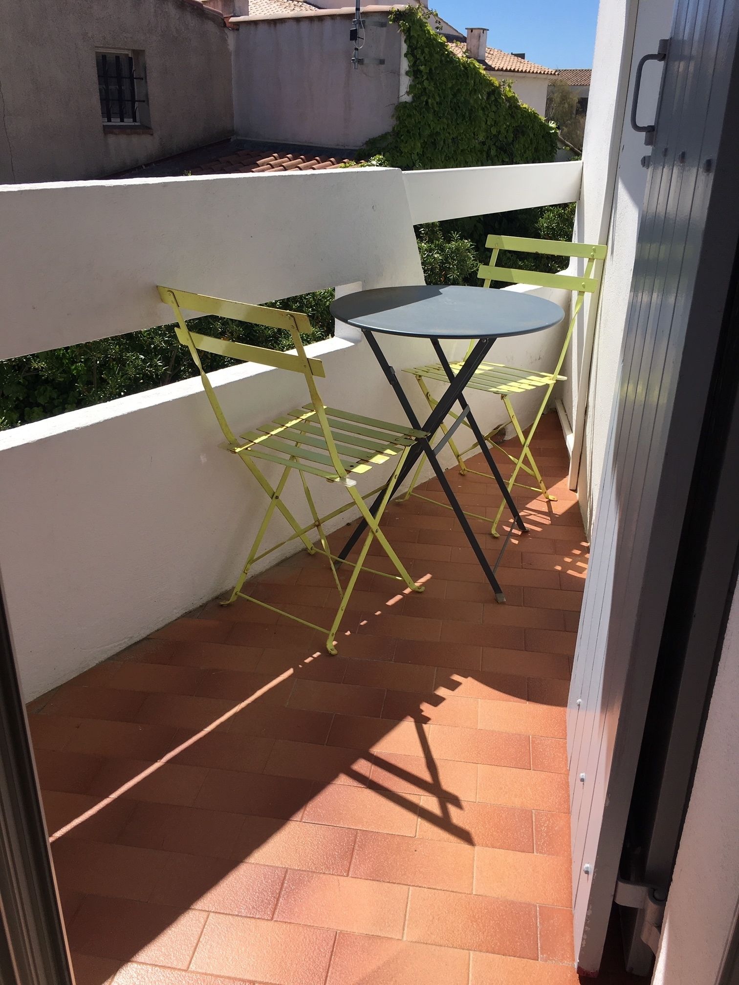 A small outdoor patio with a round table and yellow folding chairs.