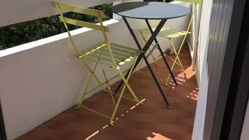 A small outdoor patio with a round table and yellow folding chairs.