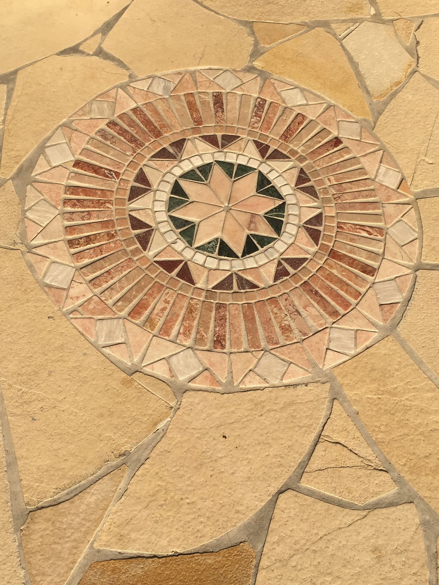 A circular mosaic tile design with a star pattern in the center.