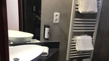 Un baño moderno con un lavamanos grande de color blanco, un calentador de toallas y un espejo.