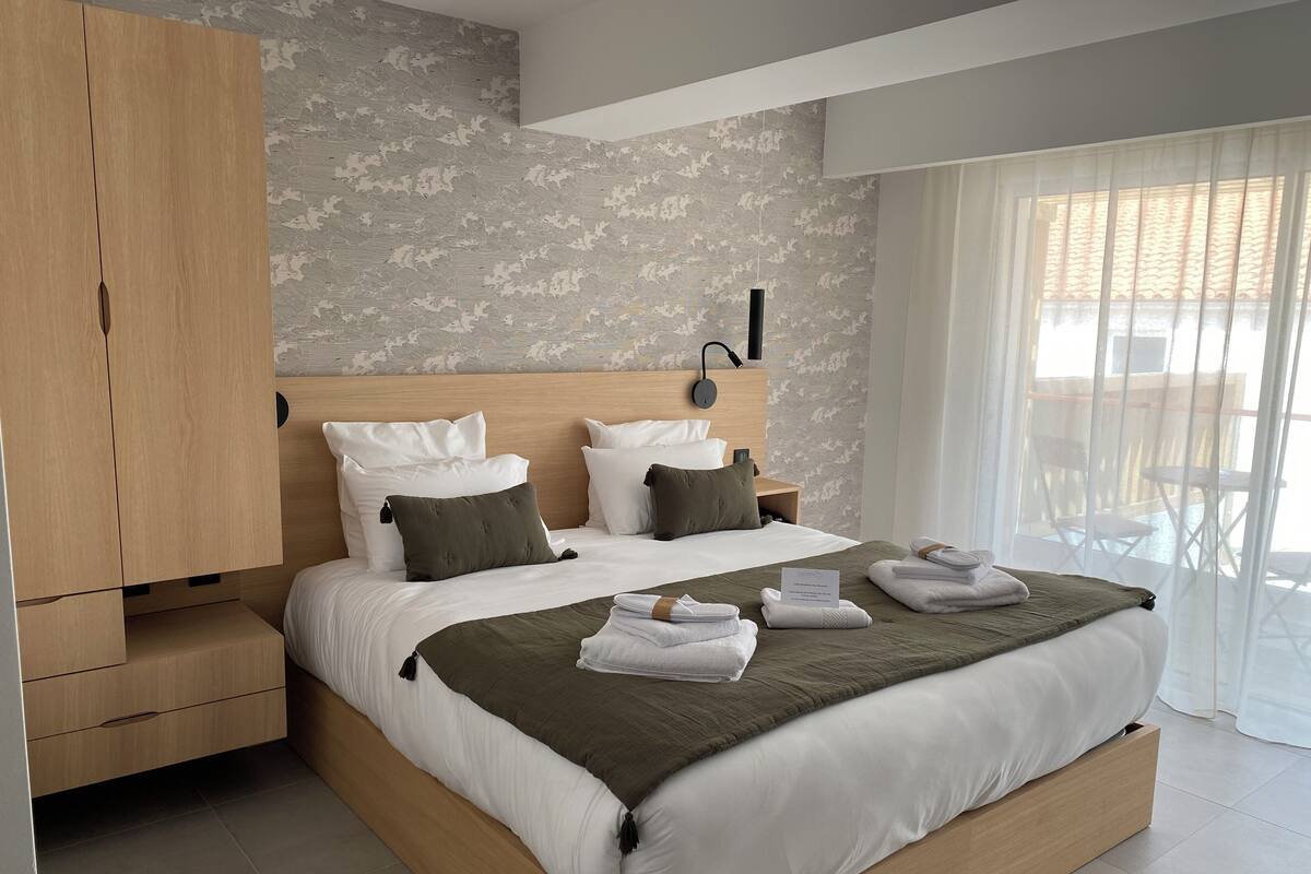 A modern bedroom with a large bed, wooden wardrobe, and a view of the outdoors.