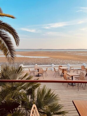 A deck with outdoor seating overlooking a beach.