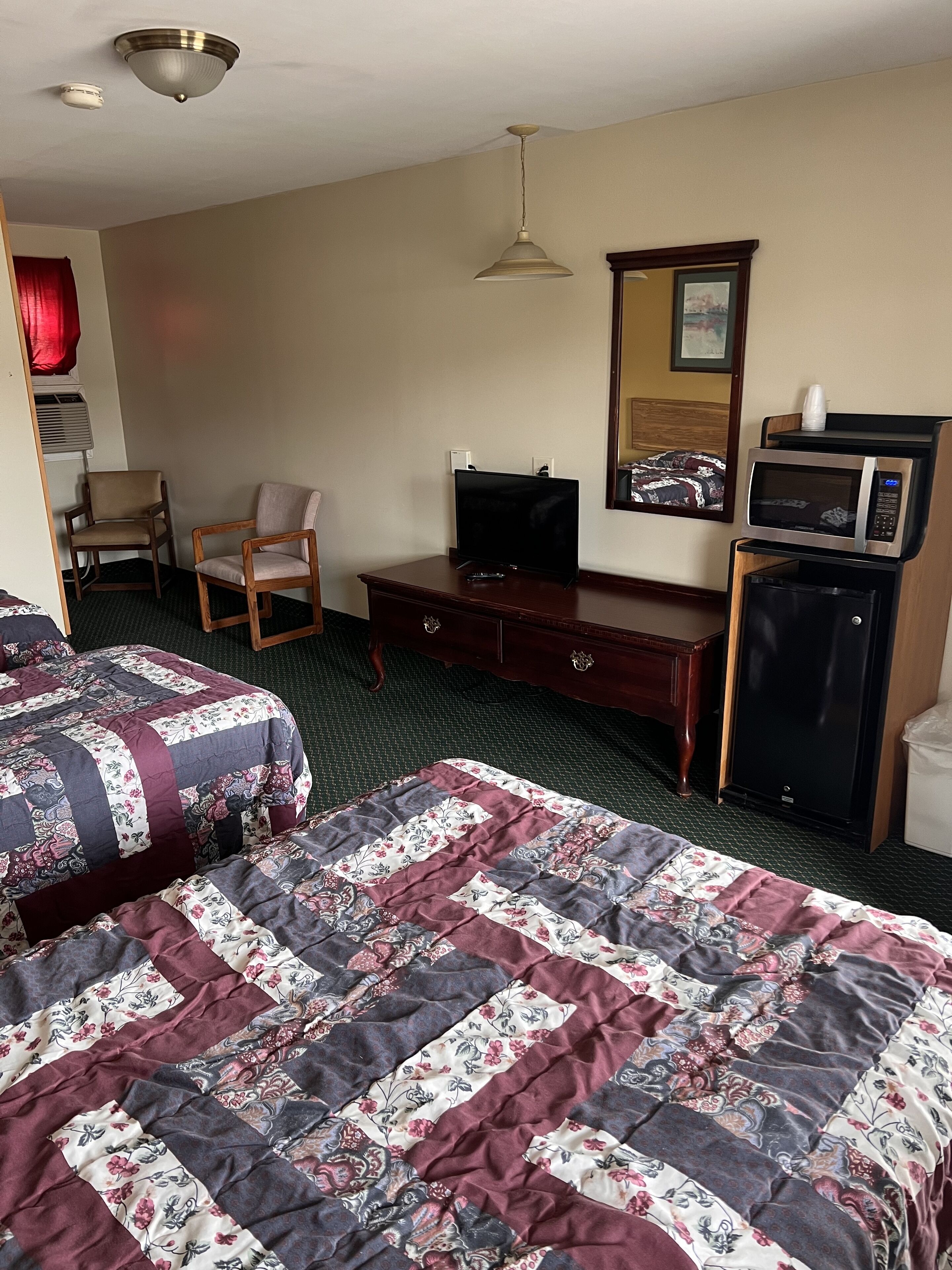 Une chambre d’hôtel avec deux lits, une télévision, un four à micro-ondes et une commode.