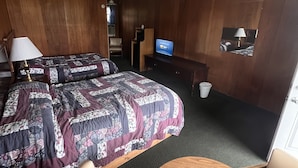 Una habitación de hotel con dos camas, televisión, escritorio y una silla.