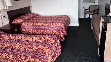 Quarto de hotel com duas camas, uma escrivaninha, uma cadeira e uma televisão.