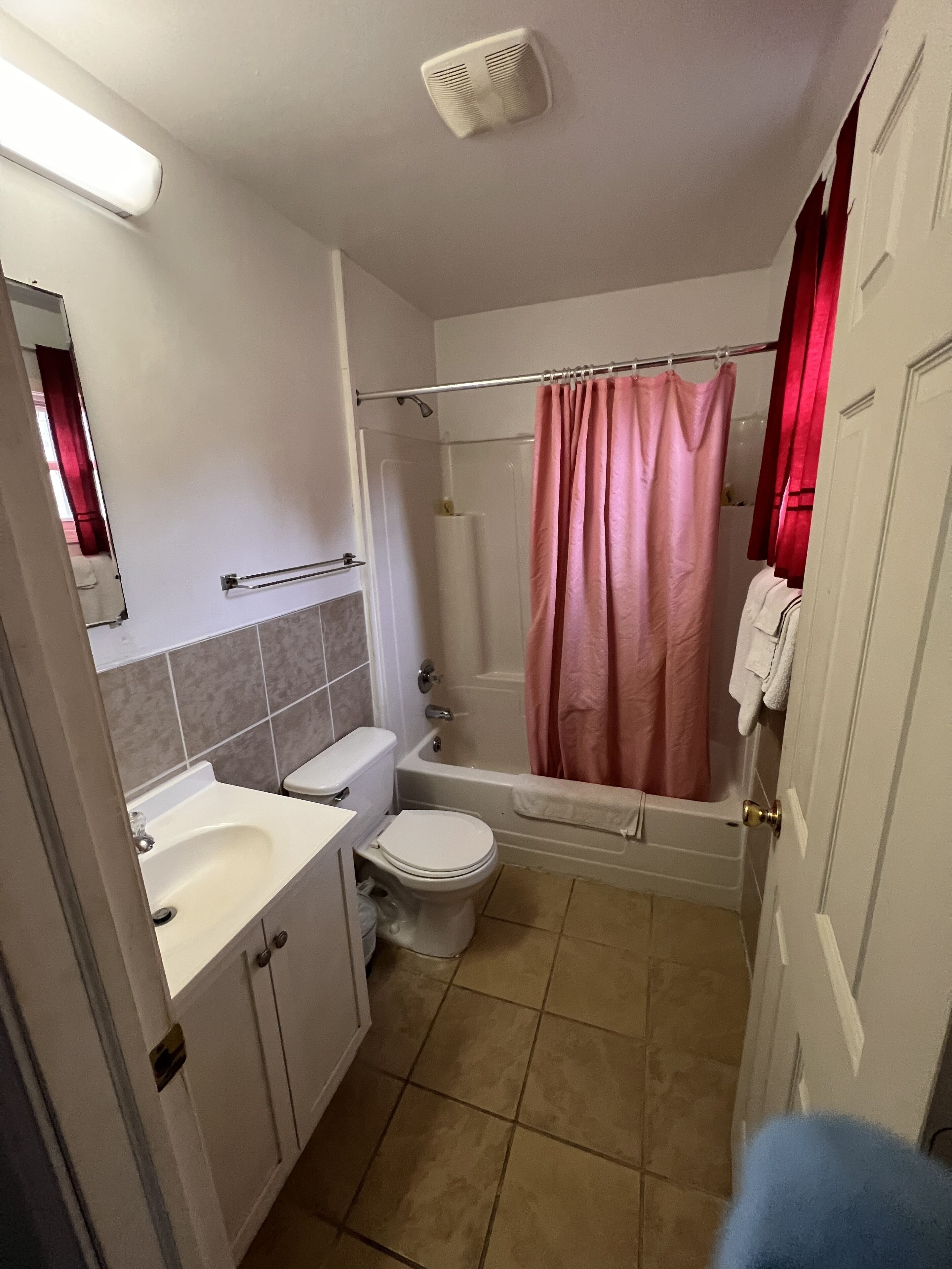 Une salle de bain équipée de toilettes, d’un lavabo, d’une baignoire et d’un rideau de douche.
