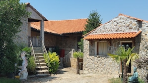 Un bâtiment en pierre avec un toit recouvert de tuiles, un escalier menant à un porche et une statue représentant une figure assise.