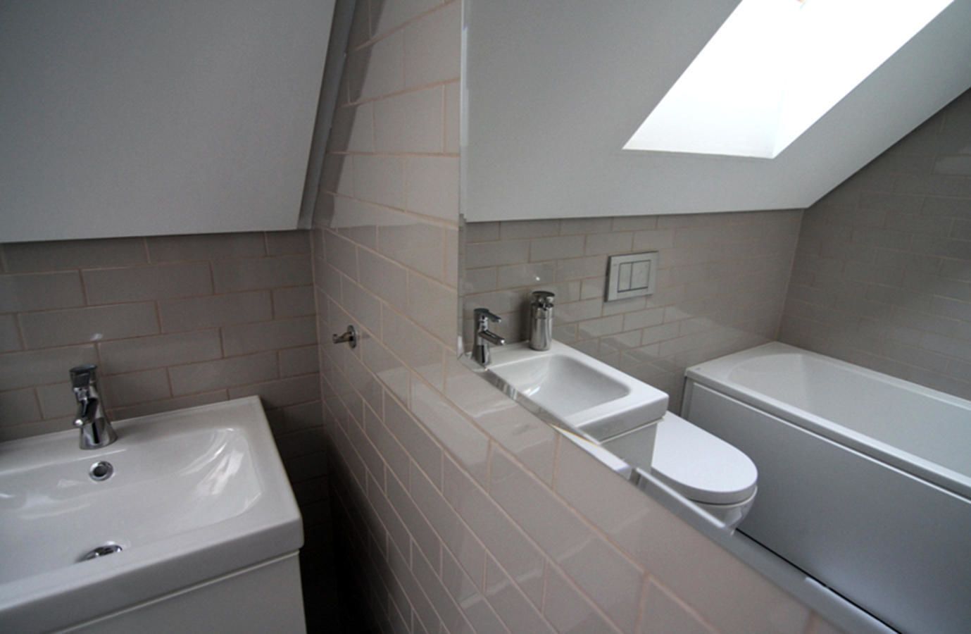 Moderni kylpyhuone, jossa on kattovalokuvio, pesuallas, wc ja kylpyamme.