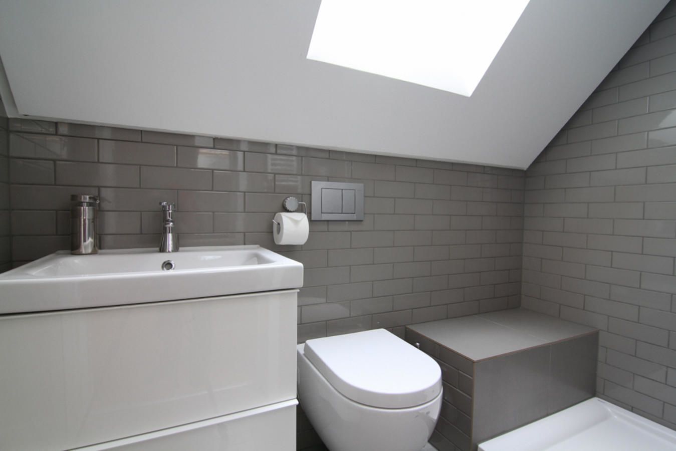 Un baño moderno con tragaluz, lavamanos, inodoro y bañera.