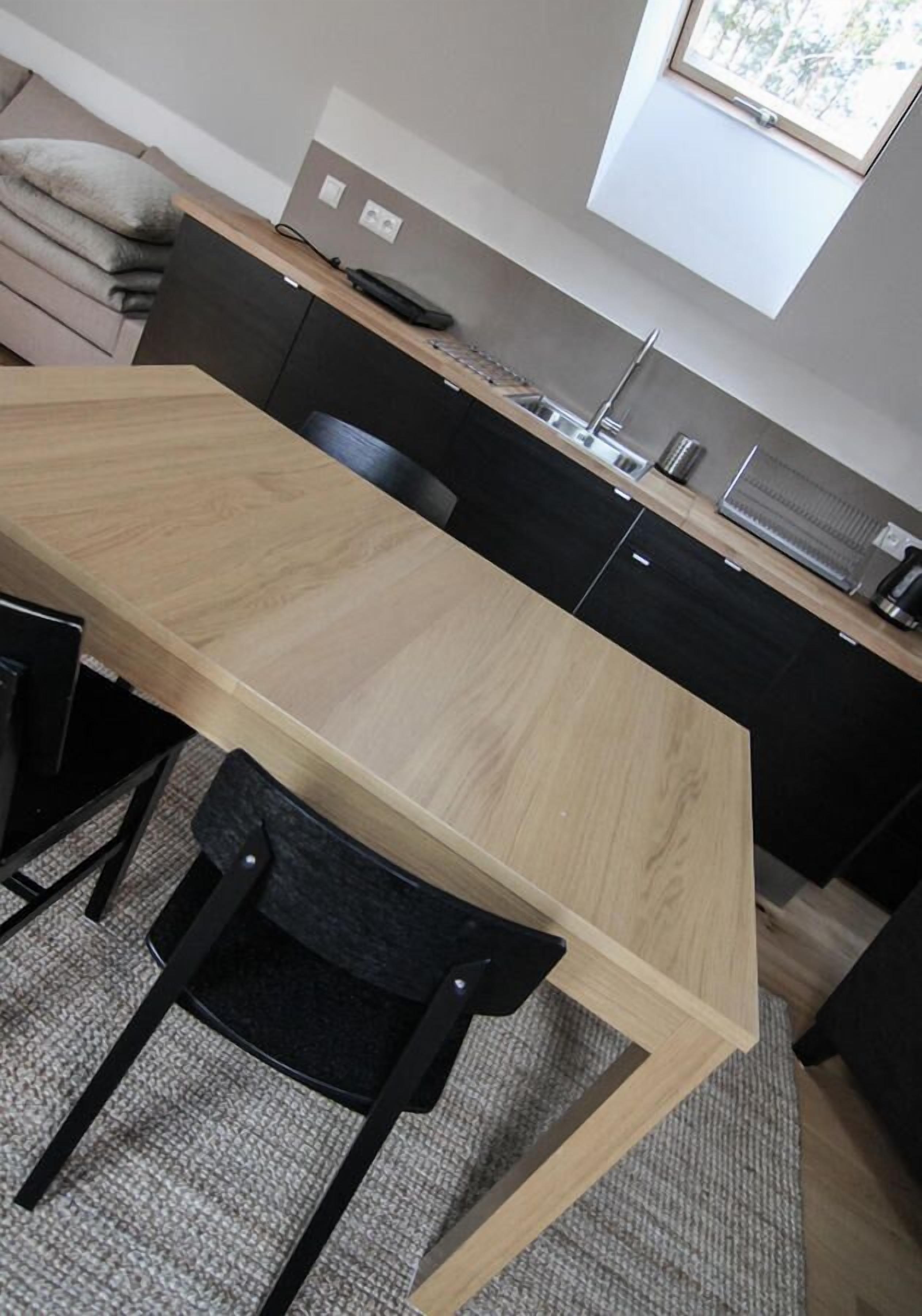 Een moderne keuken met een houten tafel en zwarte stoelen.