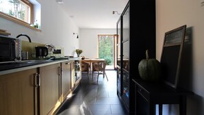 Uma cozinha moderna com área de jantar, uma janela grande e um armário preto decorado com uma abóbora.