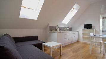 Een modern loft appartement met een eetgedeelte, kitchenette en een groot raam dat natuurlijk licht binnenlaat.