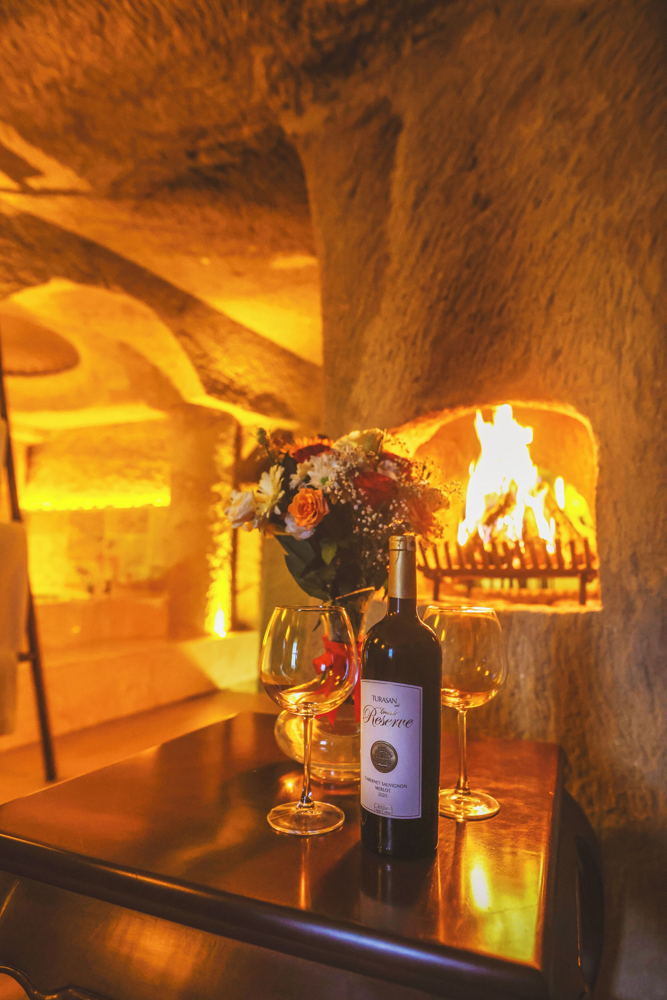 A bottle of wine on a table with a fire in the background.