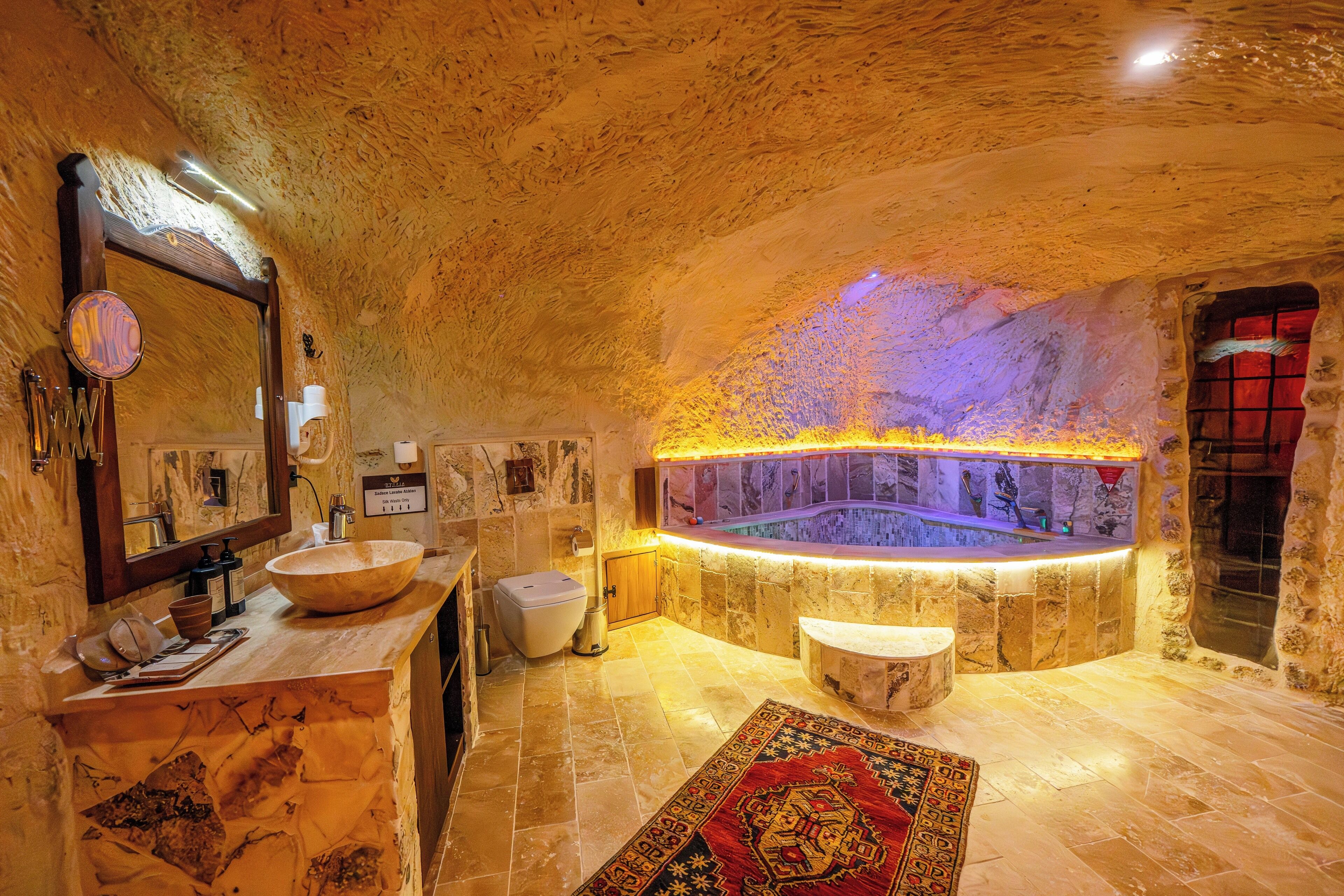 Un baño lujoso con un lavamanos grande de piedra, una bañera y un espejo.