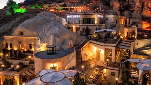 Un hotel con un exterior de aspecto rocoso y zonas de estar al aire libre, y un cartel que dice 'UTOPIA'.