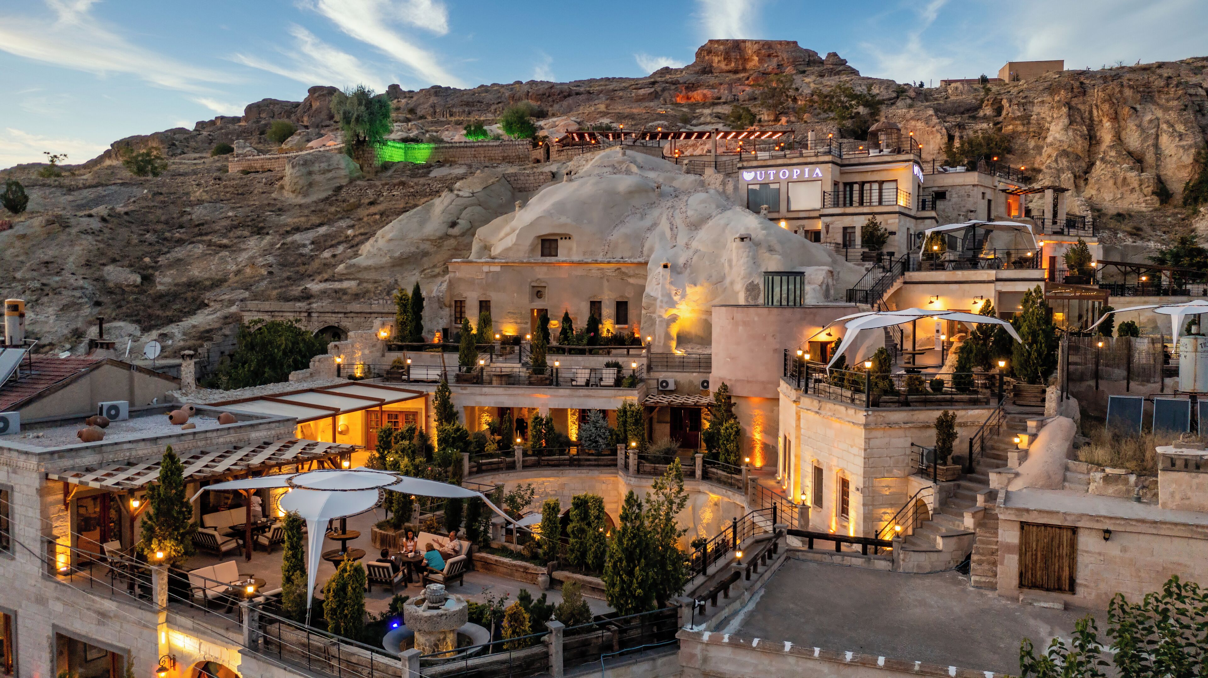A hotel with outdoor seating areas, a pool, and a view of the surrounding rocky landscape.