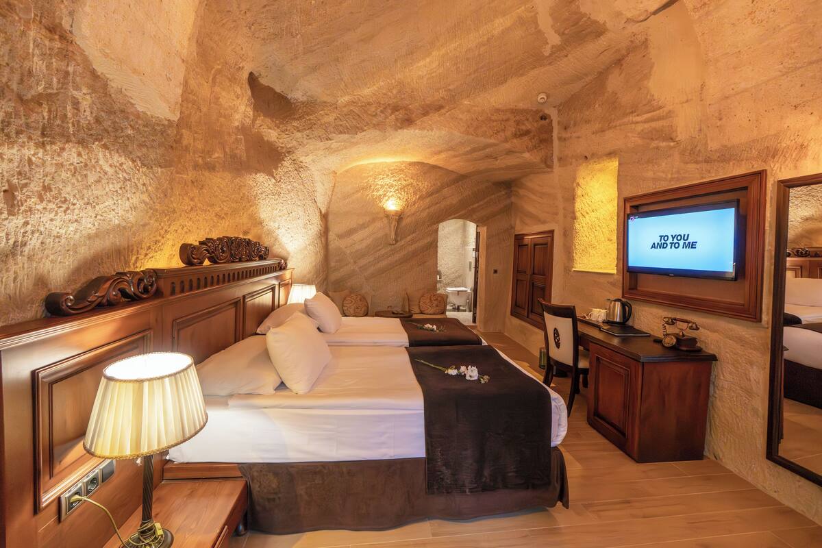 A cozy room with a bed, bedside table, lamp, and a TV screen displaying "TO YOU AND TO ME".