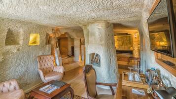 Una habitación con paredes de piedra, chimenea, una mesa de centro de madera y un espejo grande.