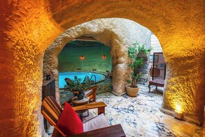 A stone archway leading to a pool area with a wooden bench and a potted plant. - Utopia Cave Cappadocia (Ürgüp)
