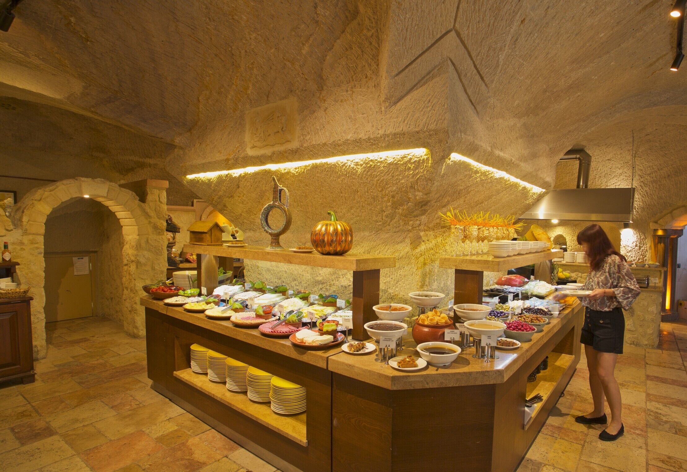 A buffet setup in a stone-walled room with a variety of food items and a person serving.