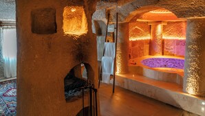 A spa area with a stone wall, a wooden ladder, and a hot tub. - Utopia Cave Cappadocia (Ürgüp)