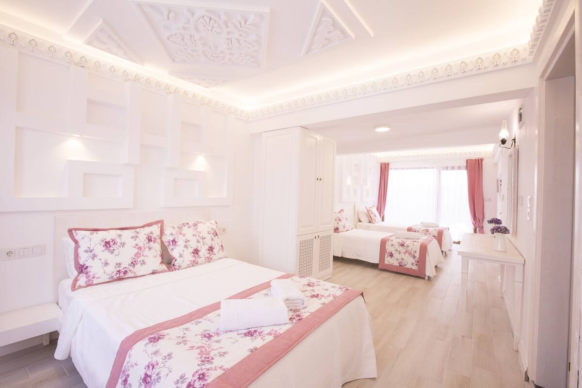 A hotel room with a large bed, a smaller bed, a desk, and a wardrobe.