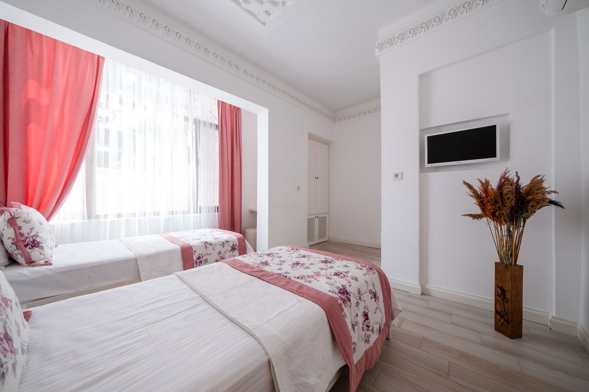 Een slaapkamer met twee bedden, een televisie en een decoratieve vaas.