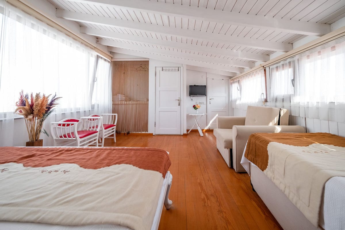 A room with two beds, a chair, a television, and a door leading to another room.