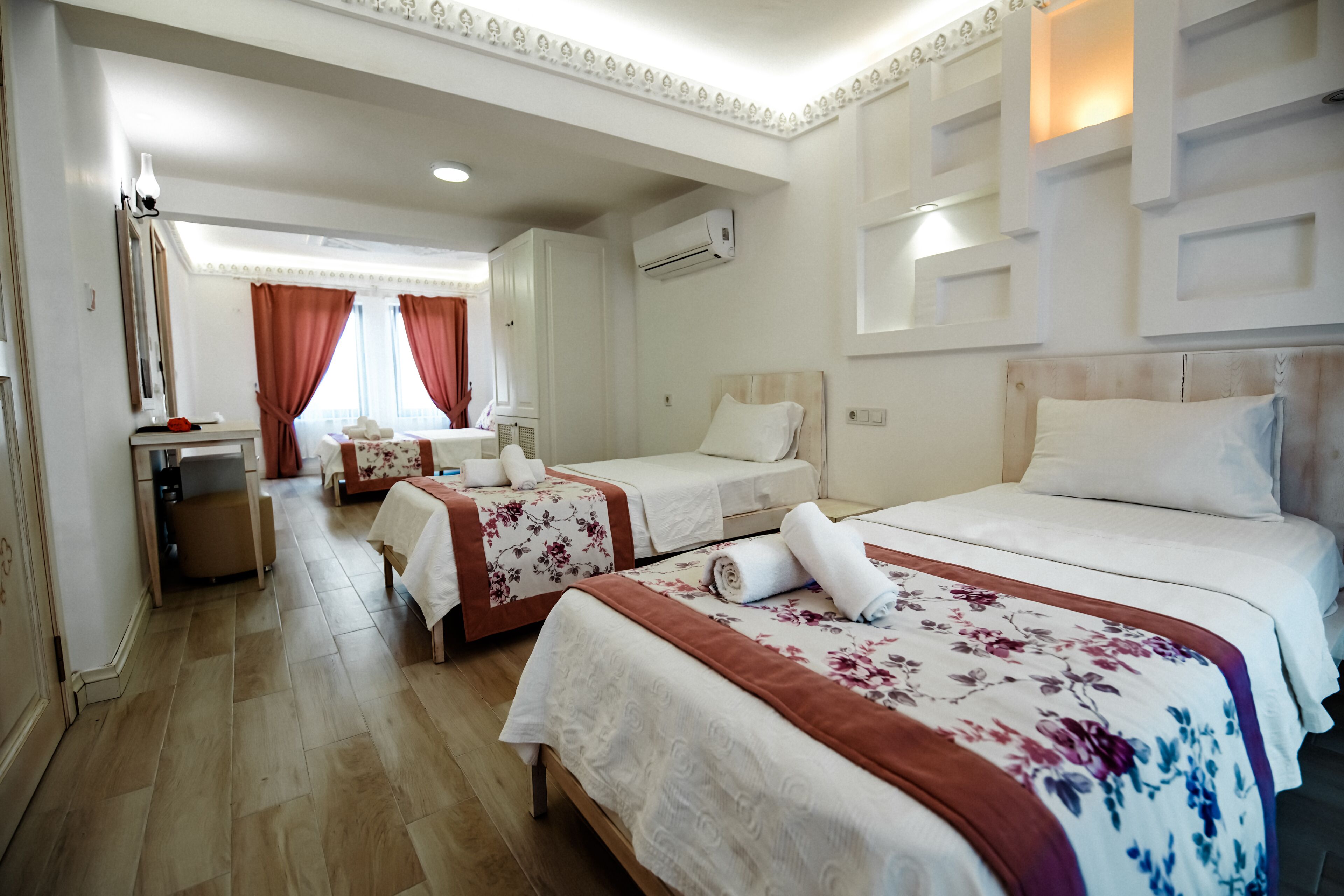 A hotel room with two beds, a desk, a chair, and a mirror.