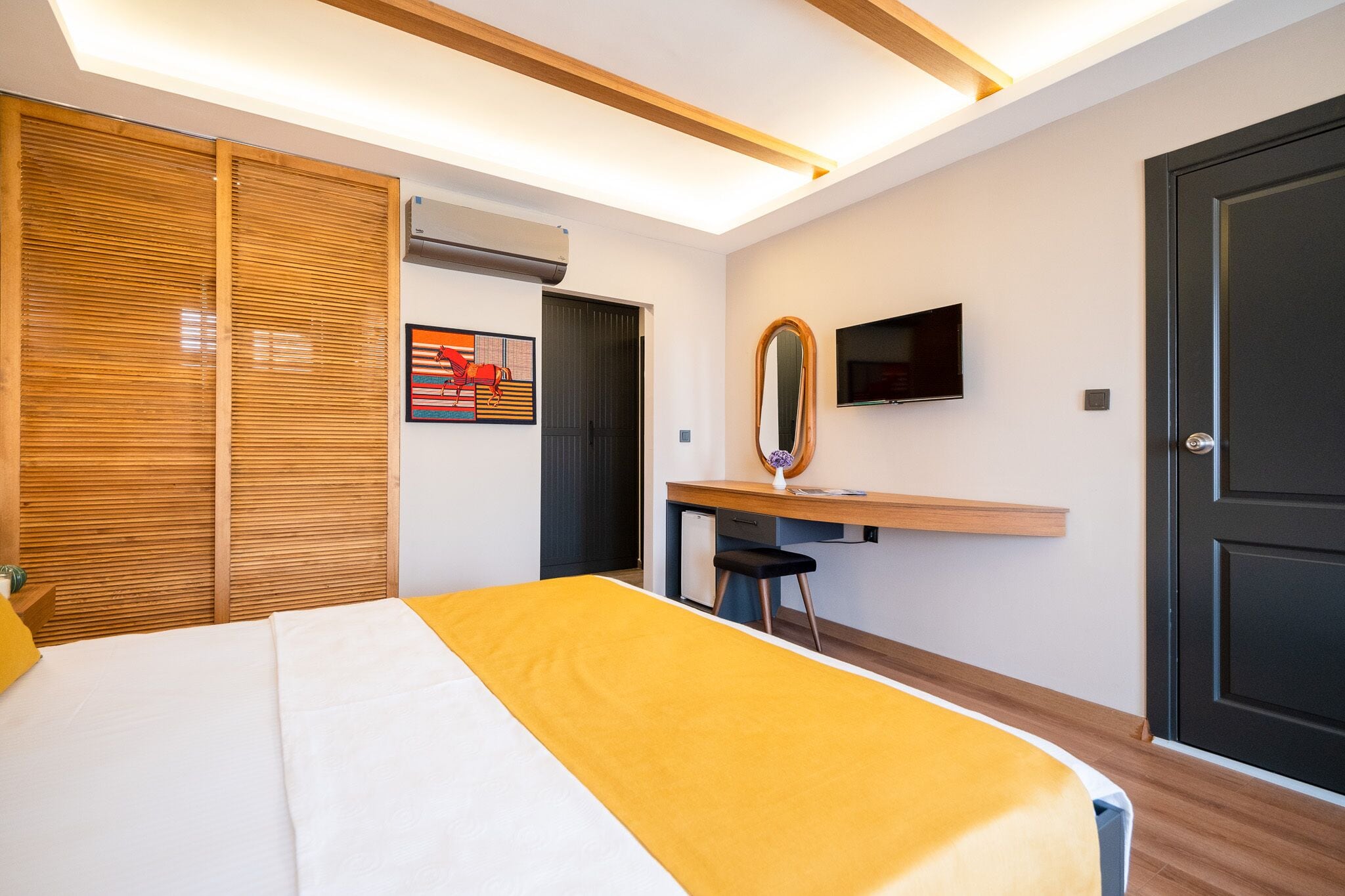 A hotel room with a bed, a desk, a chair, a TV, and a wardrobe.