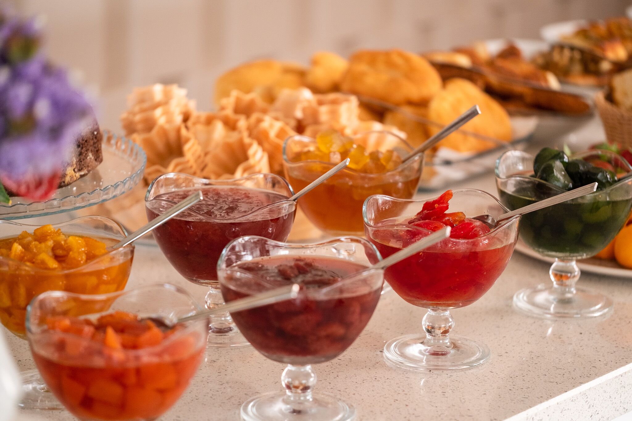 Un bufé con diversos platos y postres, incluyendo cuencos de fruta y una selección de pastelería.